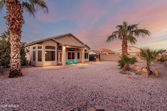 back house at dusk featuring a patio