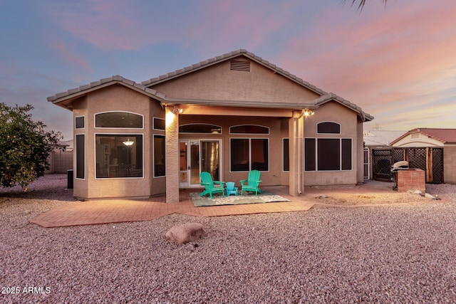 back house at dusk featuring a patio