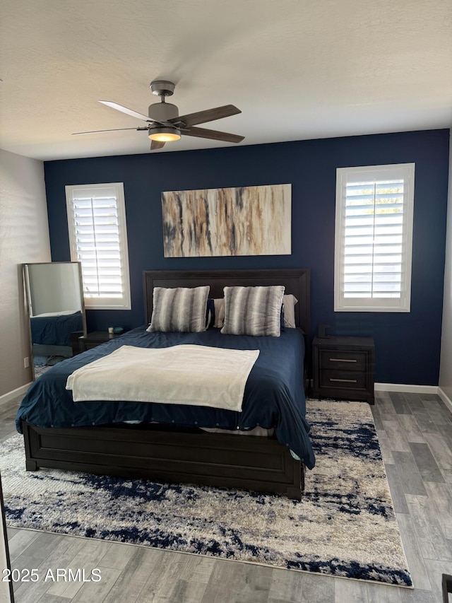 bedroom featuring multiple windows, wood-type flooring, and ceiling fan