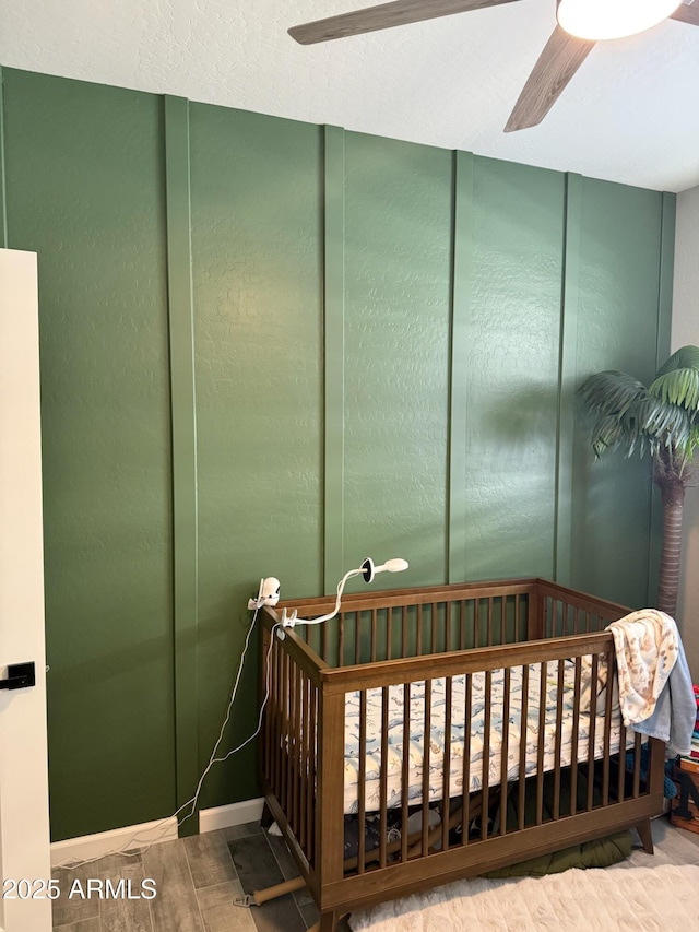 bedroom with ceiling fan, wood-type flooring, a closet, and a crib