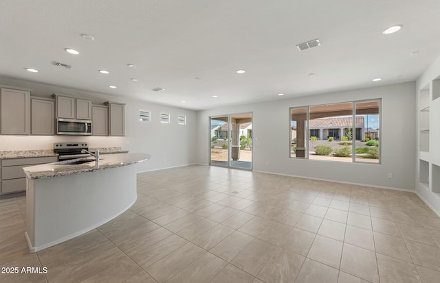 kitchen featuring stainless steel appliances, recessed lighting, gray cabinets, visible vents, and light stone countertops