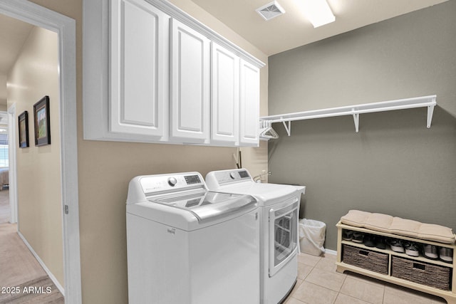 washroom featuring washer and clothes dryer, cabinets, and light tile patterned floors