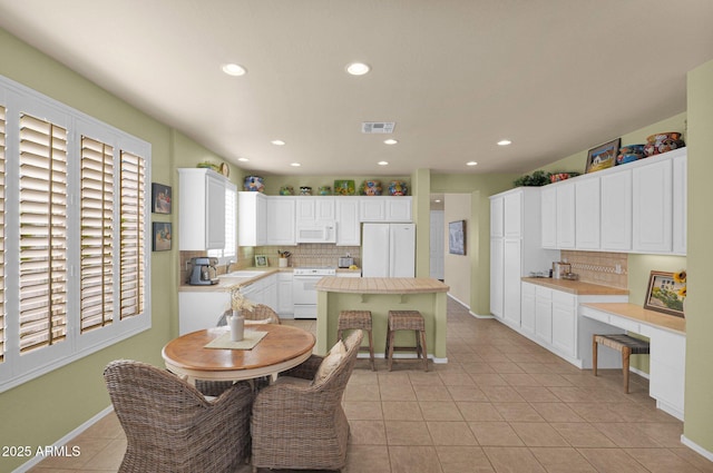 kitchen with backsplash, sink, white cabinets, and white appliances