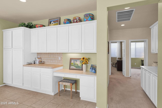 kitchen with white cabinets, backsplash, and light colored carpet