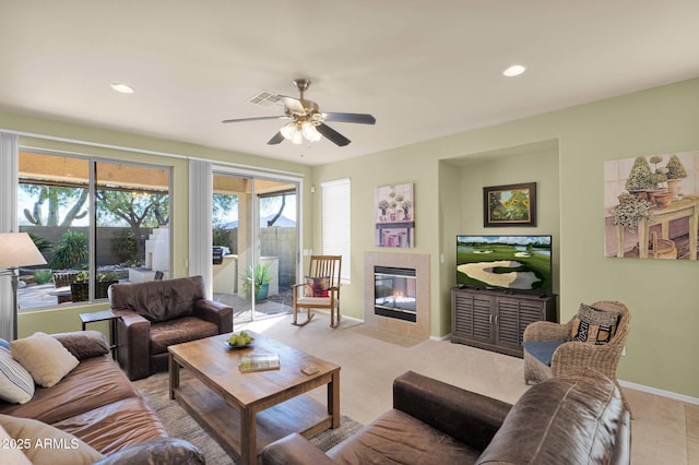 living room featuring ceiling fan and a tiled fireplace