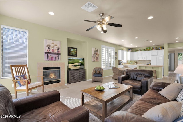 living room featuring ceiling fan and a tiled fireplace