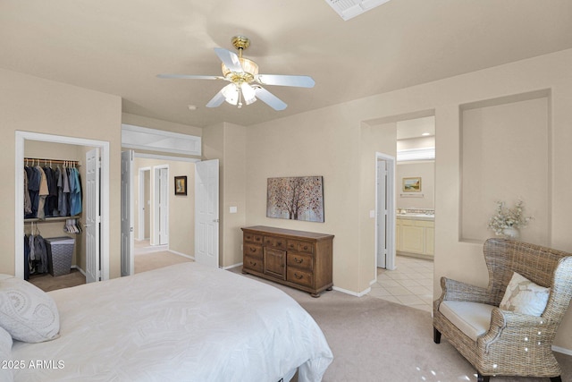 bedroom featuring connected bathroom, ceiling fan, a walk in closet, light carpet, and a closet