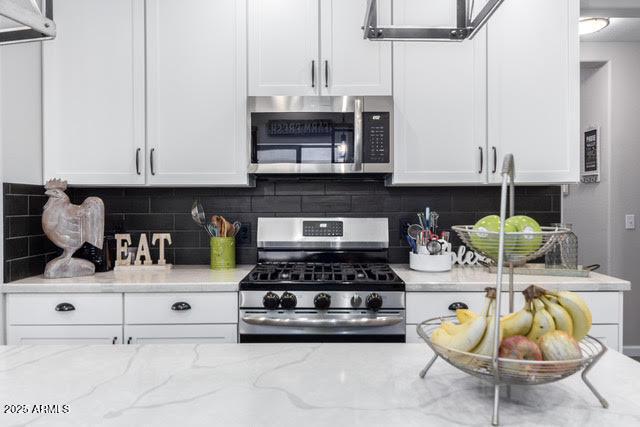 kitchen with appliances with stainless steel finishes, white cabinetry, and light stone counters