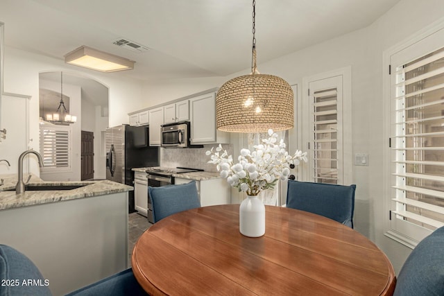 19812 N 90th Dr, Peoria, AZ 85382 - dining room featuring a chandelier, visible vents, arched walkways, and vaulted ceiling