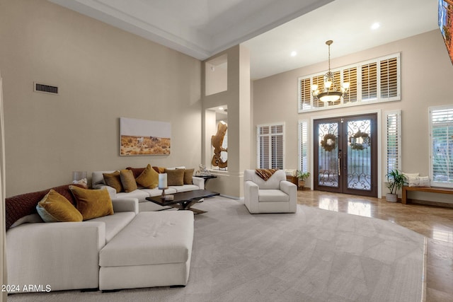 living room with a notable chandelier, a high ceiling, and french doors