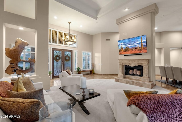 living room featuring a high end fireplace, a towering ceiling, and a notable chandelier