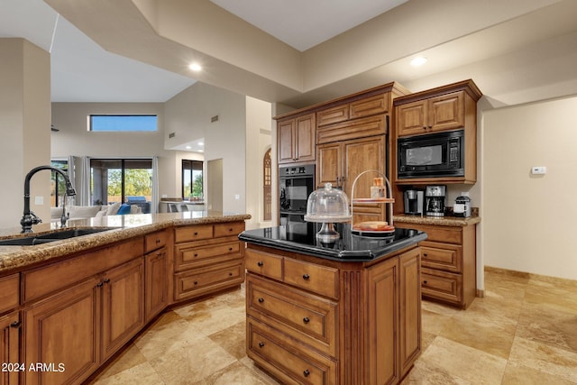 kitchen with sink, black appliances, dark stone countertops, a high ceiling, and a center island