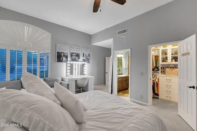 carpeted bedroom featuring a walk in closet, ensuite bath, ceiling fan, sink, and a closet