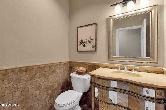 bathroom with vanity, toilet, and tile walls