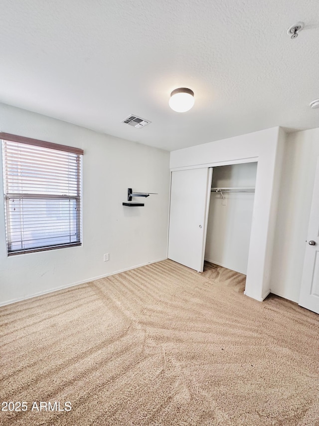 unfurnished bedroom with light carpet, a closet, and a textured ceiling