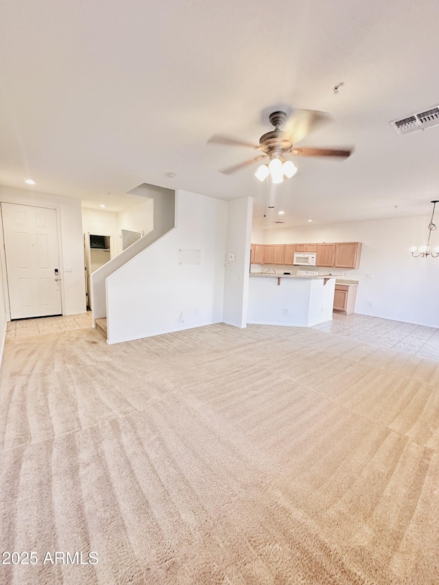 unfurnished living room featuring light colored carpet and ceiling fan with notable chandelier