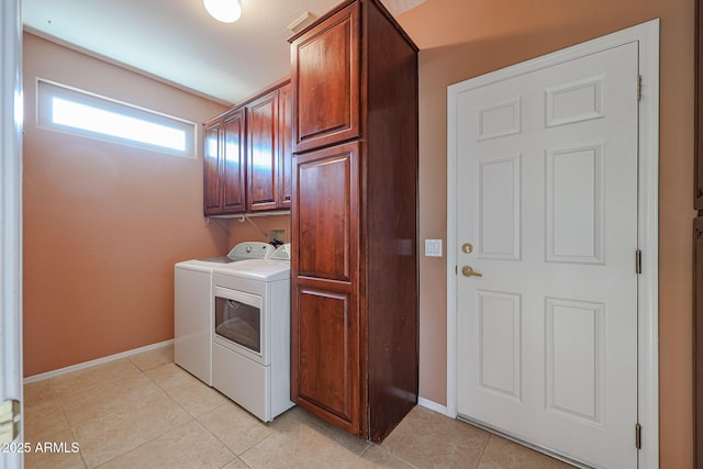 clothes washing area with cabinets, separate washer and dryer, and light tile patterned floors