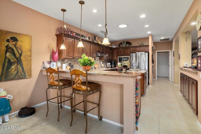 kitchen featuring built in microwave, stainless steel fridge, kitchen peninsula, light stone countertops, and decorative backsplash