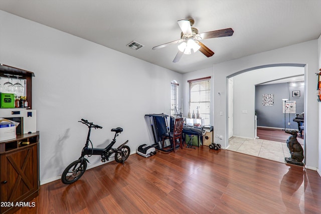 exercise room with ceiling fan and light hardwood / wood-style flooring