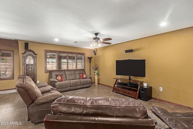 living room featuring baseboards, ceiling fan, visible vents, and a textured ceiling