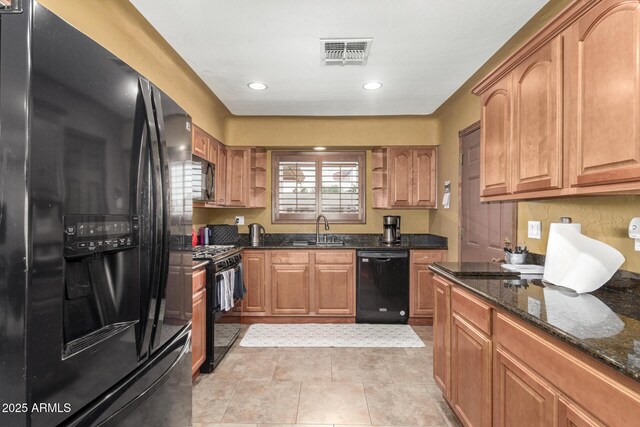 kitchen featuring recessed lighting, visible vents, a sink, dark stone countertops, and black appliances