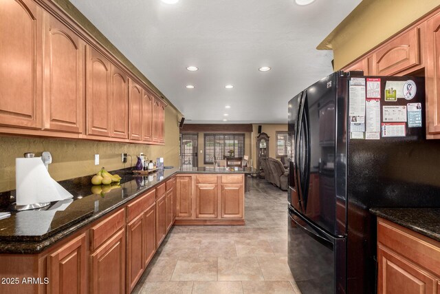 kitchen with a peninsula, recessed lighting, dark stone countertops, and freestanding refrigerator