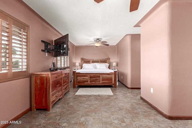 bedroom featuring ceiling fan, a textured ceiling, and baseboards