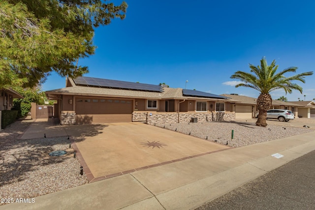 single story home featuring concrete driveway, stone siding, an attached garage, and a gate