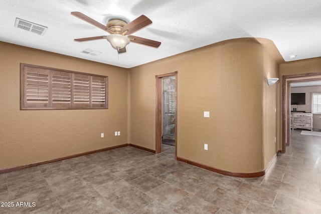 empty room featuring baseboards, visible vents, and ceiling fan