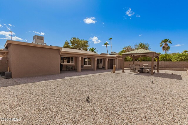 rear view of house featuring a patio, stucco siding, a gazebo, central AC unit, and fence