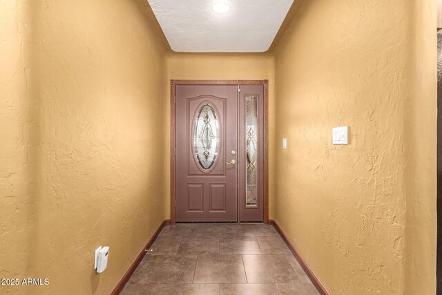 doorway with a textured wall and baseboards