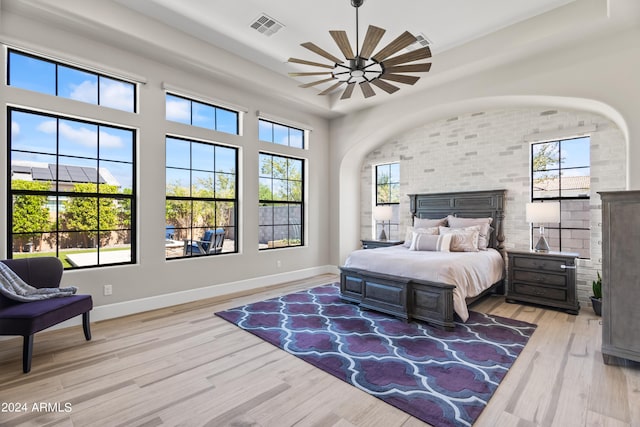 bedroom with light wood-type flooring, ceiling fan, and multiple windows