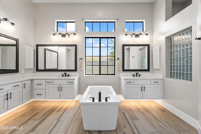 bathroom with vanity, a high ceiling, hardwood / wood-style floors, and a tub to relax in