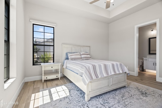 bedroom with ensuite bath, ceiling fan, and light hardwood / wood-style floors