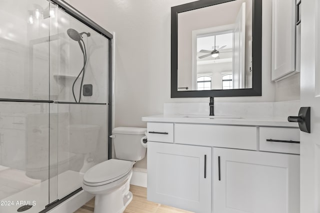 bathroom with toilet, an enclosed shower, vanity, and ceiling fan