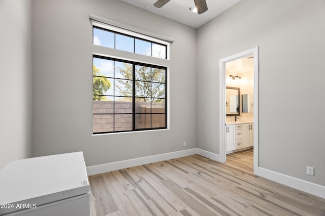 unfurnished bedroom with ensuite bath, ceiling fan, and light hardwood / wood-style floors