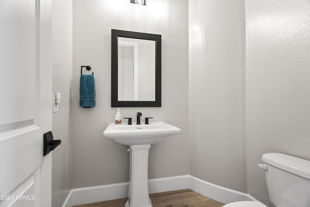 bathroom featuring toilet, sink, and hardwood / wood-style floors