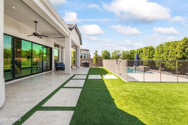 view of yard featuring a patio area, ceiling fan, and a fenced in pool