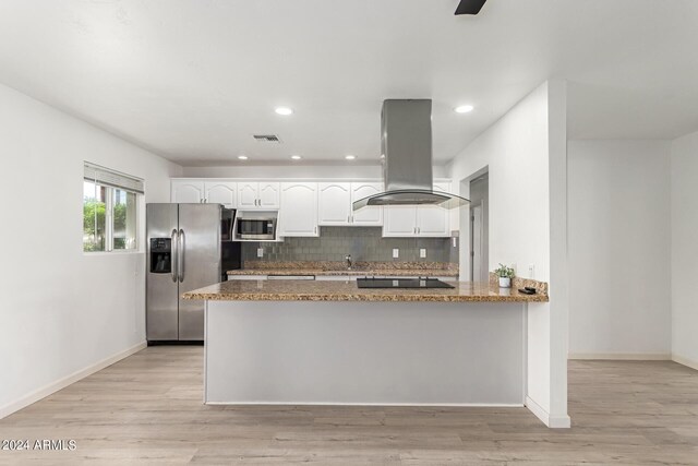 kitchen with stone counters, stainless steel appliances, island range hood, kitchen peninsula, and white cabinets