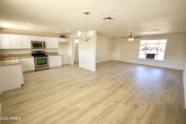 kitchen featuring pendant lighting, sink, white cabinets, stainless steel appliances, and light wood-type flooring