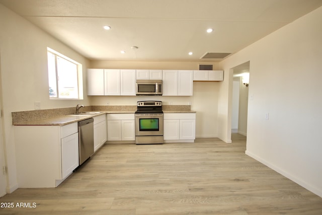 kitchen featuring white cabinetry, sink, stainless steel appliances, and light hardwood / wood-style floors