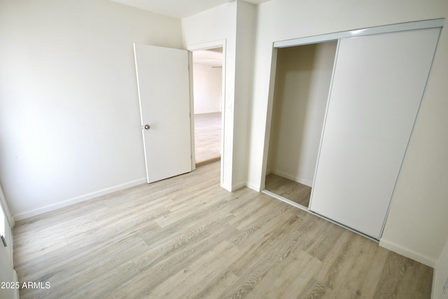 unfurnished bedroom with a closet and light wood-type flooring