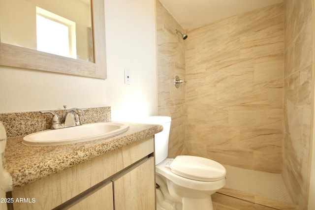 bathroom featuring vanity, tiled shower, and toilet