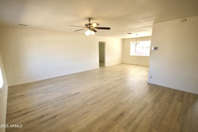 unfurnished room featuring ceiling fan with notable chandelier, light hardwood / wood-style floors, and a textured ceiling