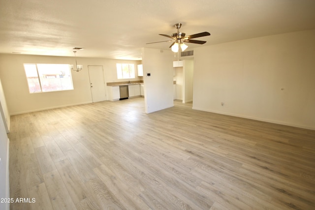 unfurnished living room with ceiling fan with notable chandelier and light hardwood / wood-style flooring