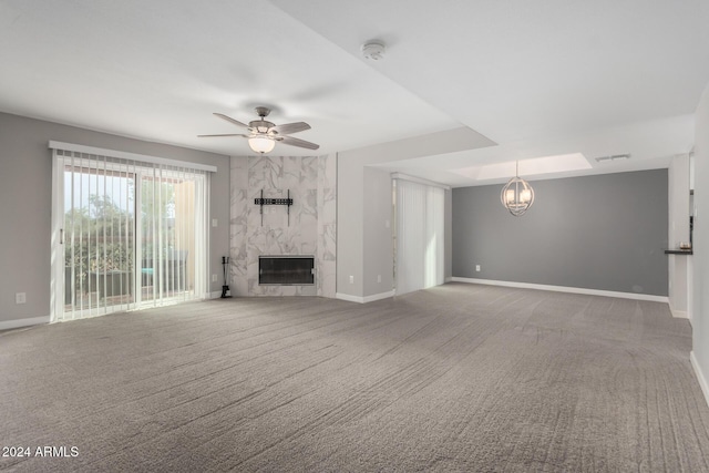 unfurnished living room with a premium fireplace, heating unit, ceiling fan with notable chandelier, and carpet floors