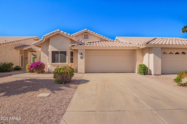 view of front of home featuring a garage, a tile roof, driveway, and stucco siding