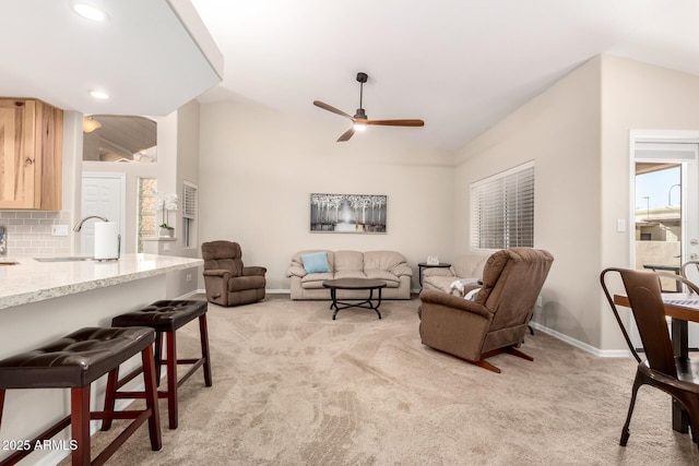 living room with light carpet, ceiling fan, baseboards, and lofted ceiling