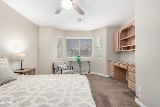 bedroom with built in desk, visible vents, a ceiling fan, light carpet, and baseboards