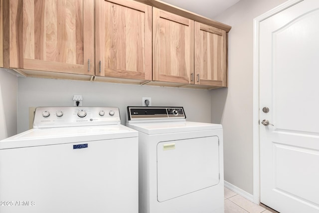 laundry room featuring light tile patterned floors, separate washer and dryer, cabinet space, and baseboards